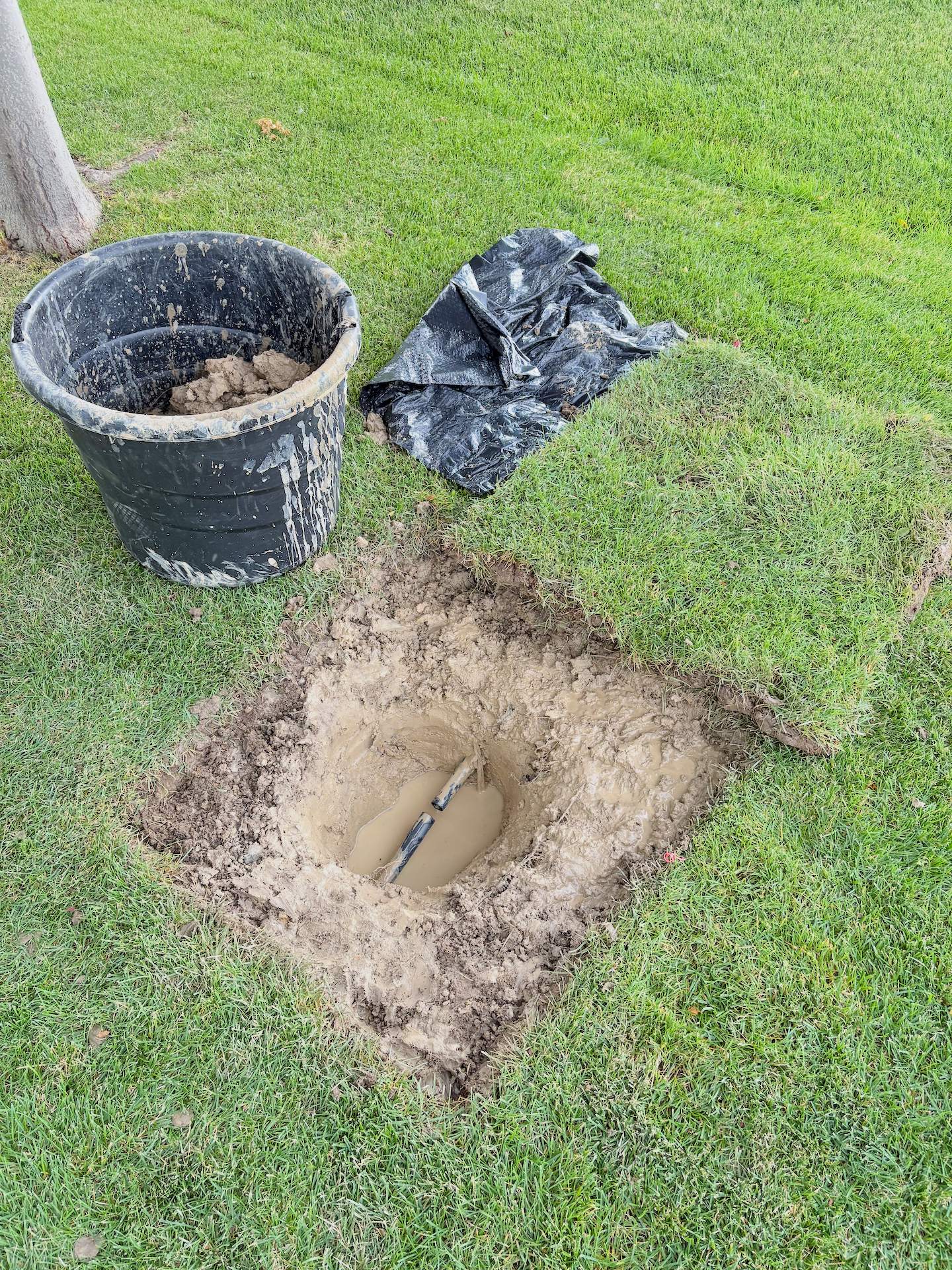 Broken sprinkler line with muddy excavation